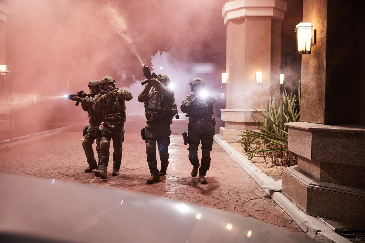 Equipe tática avançando à noite em meio a fumaça